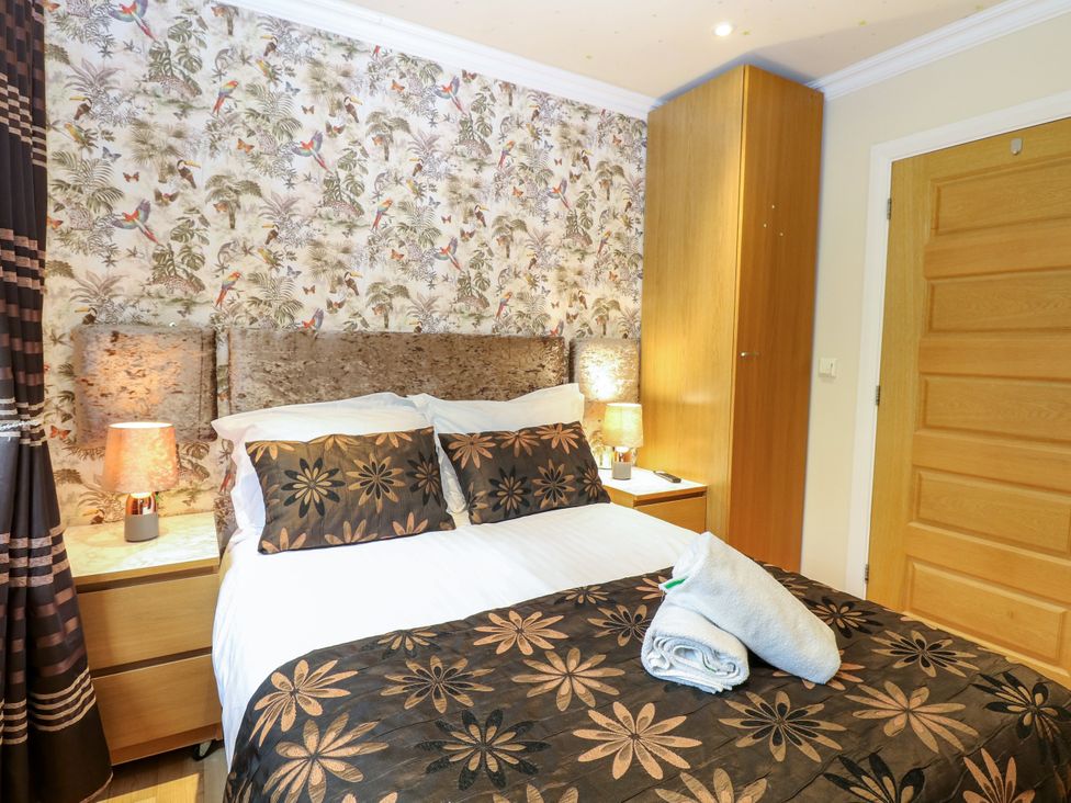 A bedroom with a bed and decorative pillows at Birch Cottage in Brundall