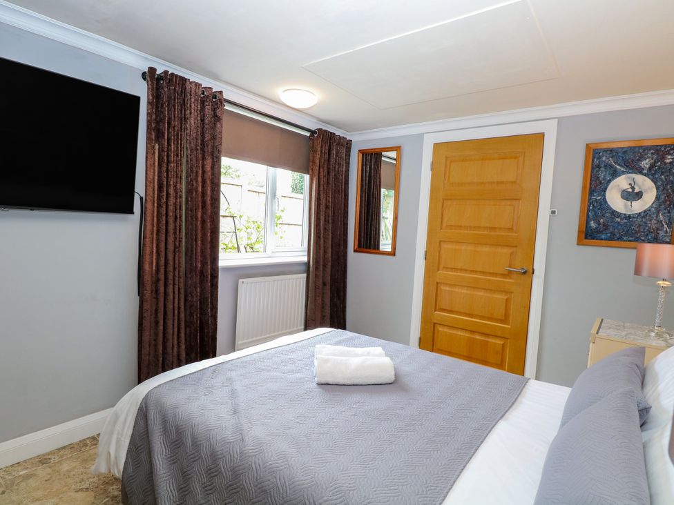 A bedroom with a bed and television at Birch Cottage in Brundall