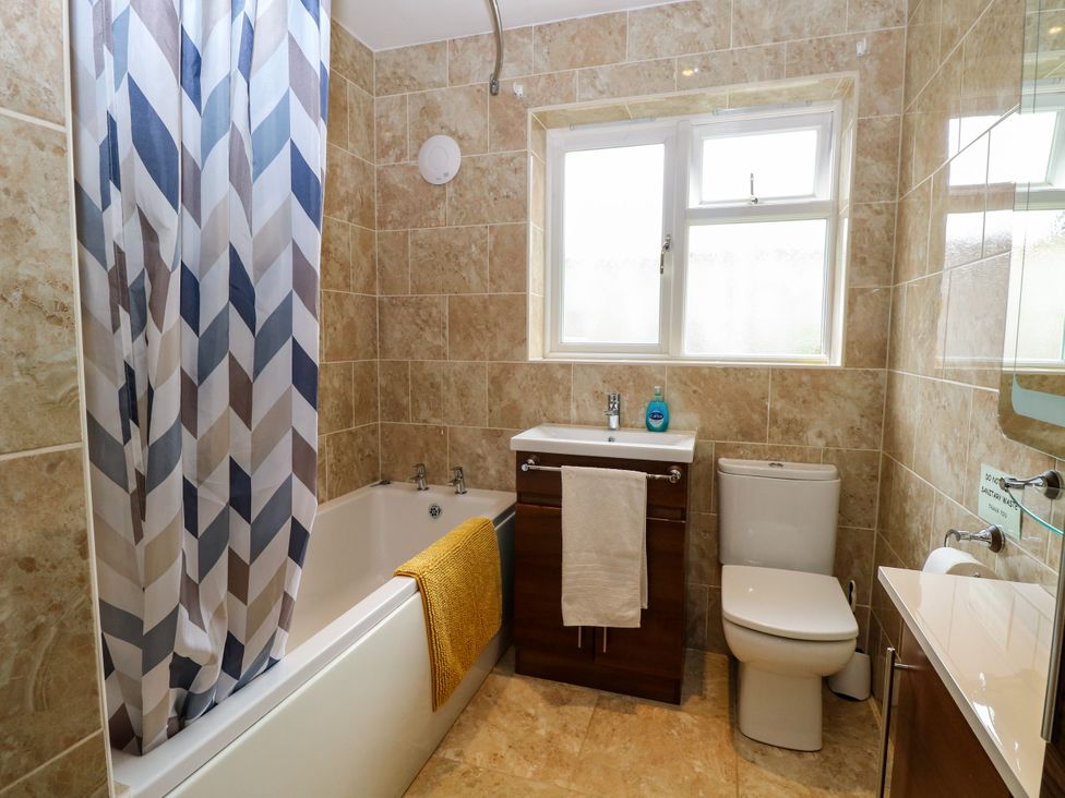 A bathroom with a bathtub, toilet, and sink at Birch Cottage in Brundall