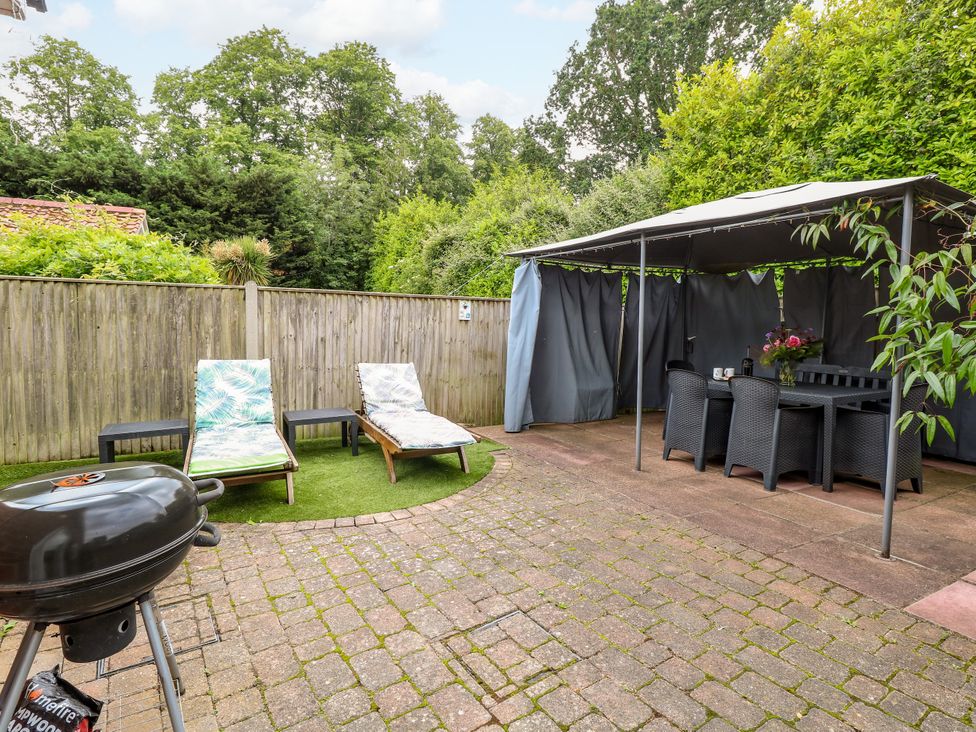 A garden with loungers and a gazebo at Birch Cottage in Brundall