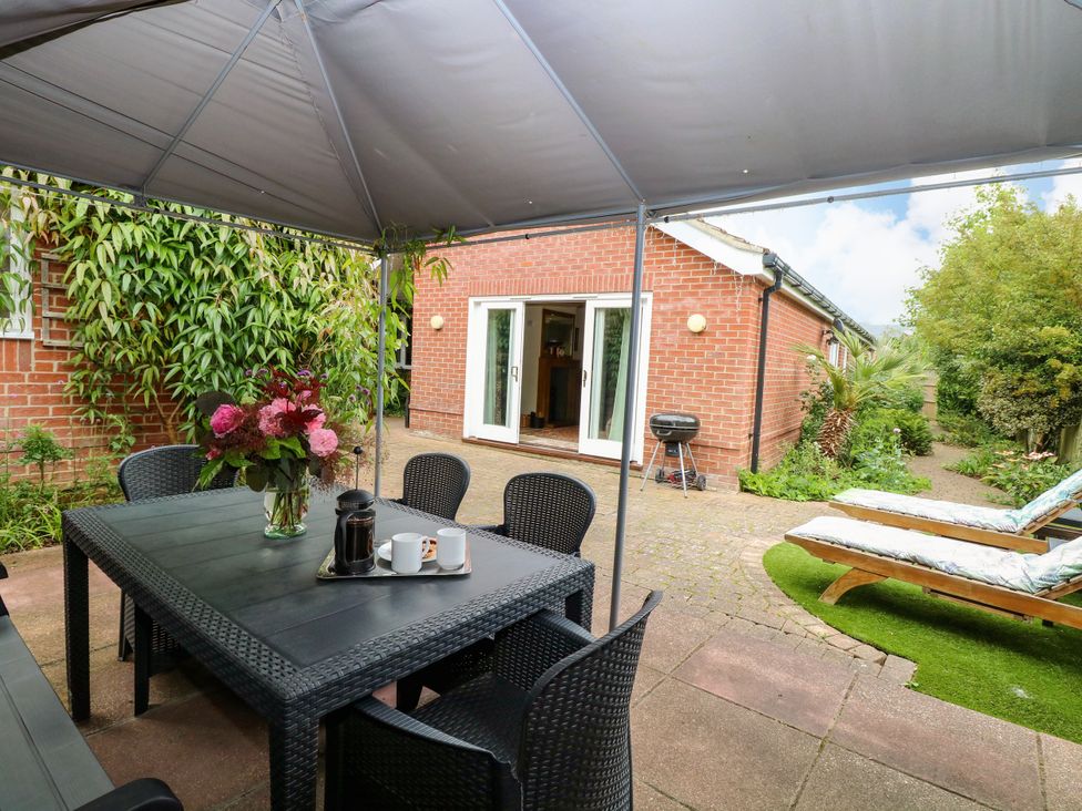 An outdoor seating area with a table and chairs at Birch Cottage in Brundall