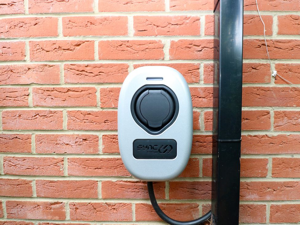 An electric vehicle charging station mounted on a brick wall at Birch Cottage in Brundall