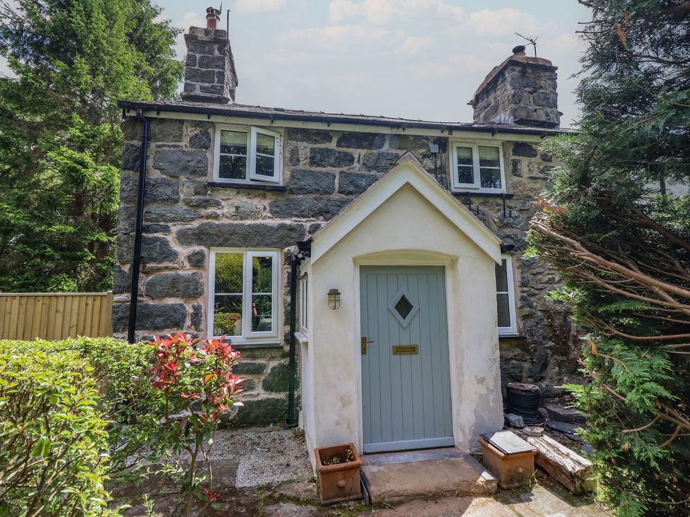 A cottage with a stone wall and front door at Islwyn near Llanuwchllyn