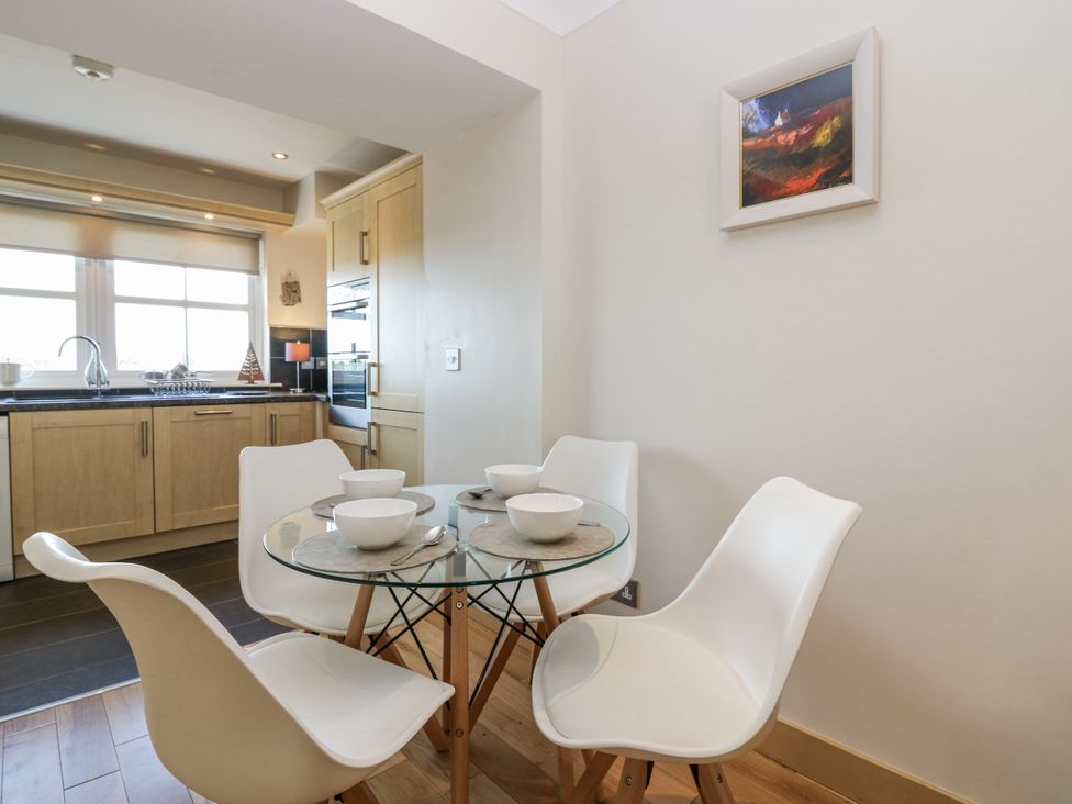 A dining room with a glass table and white chairs at 6A Pitlethie Steading in Leuchars