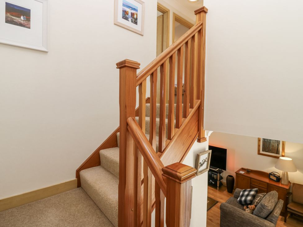 A staircase with wooden handrail and a view of a living room at 6A Pitlethie Steading Leuchars