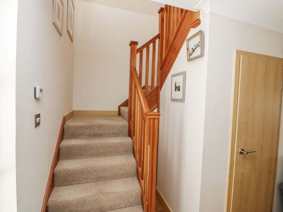 A staircase with wooden handrail and pictures on the wall at 6A Pitlethie Steading in Leuchars