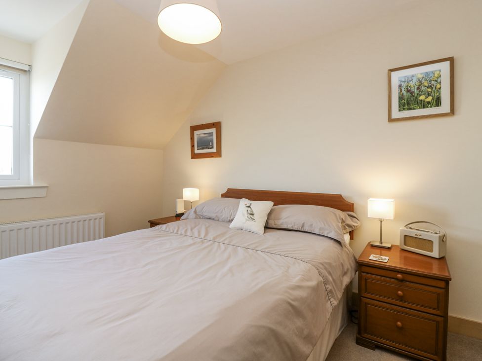 A bedroom with a bed and bedside table at 6A Pitlethie Steading in Leuchars