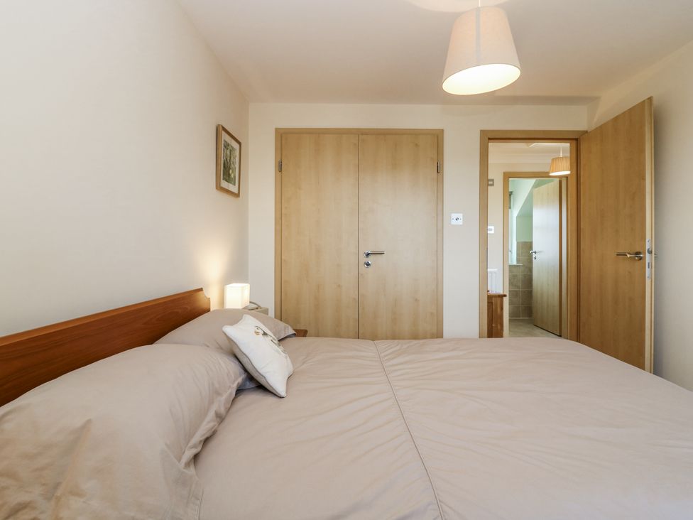 A bedroom with a bed and doors at 6A Pitlethie Steading Leuchars