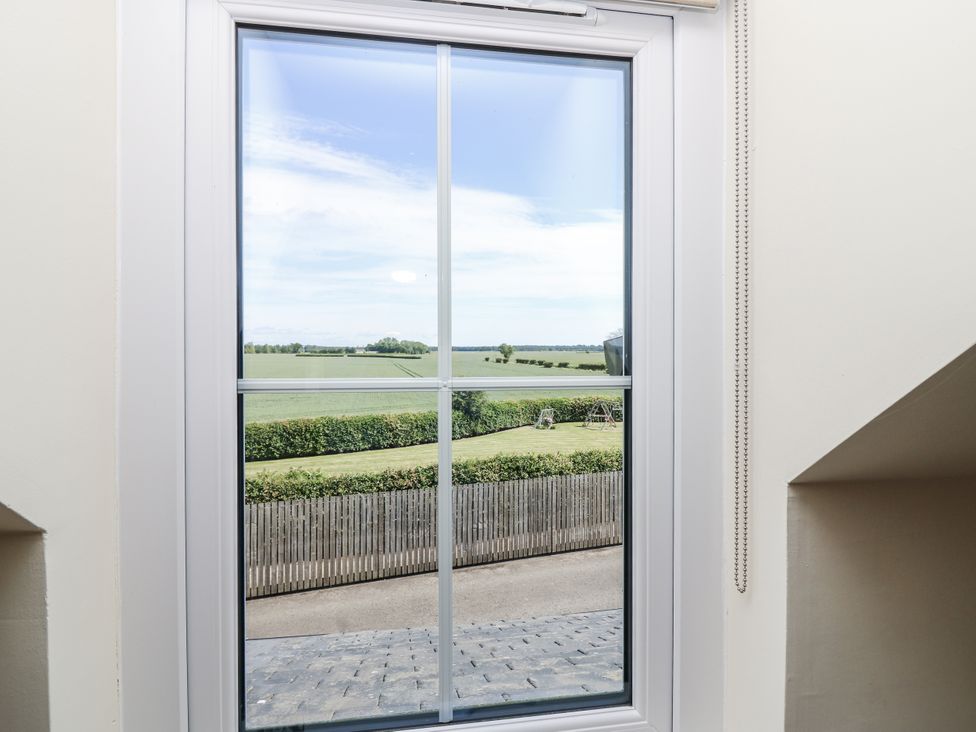 A window with a view of grass and a swing set at 6A Pitlethie Steading Leuchars