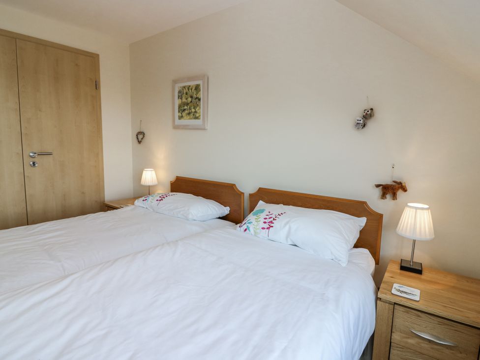 A bedroom with two beds and a nightstand at 6A Pitlethie Steading Leuchars
