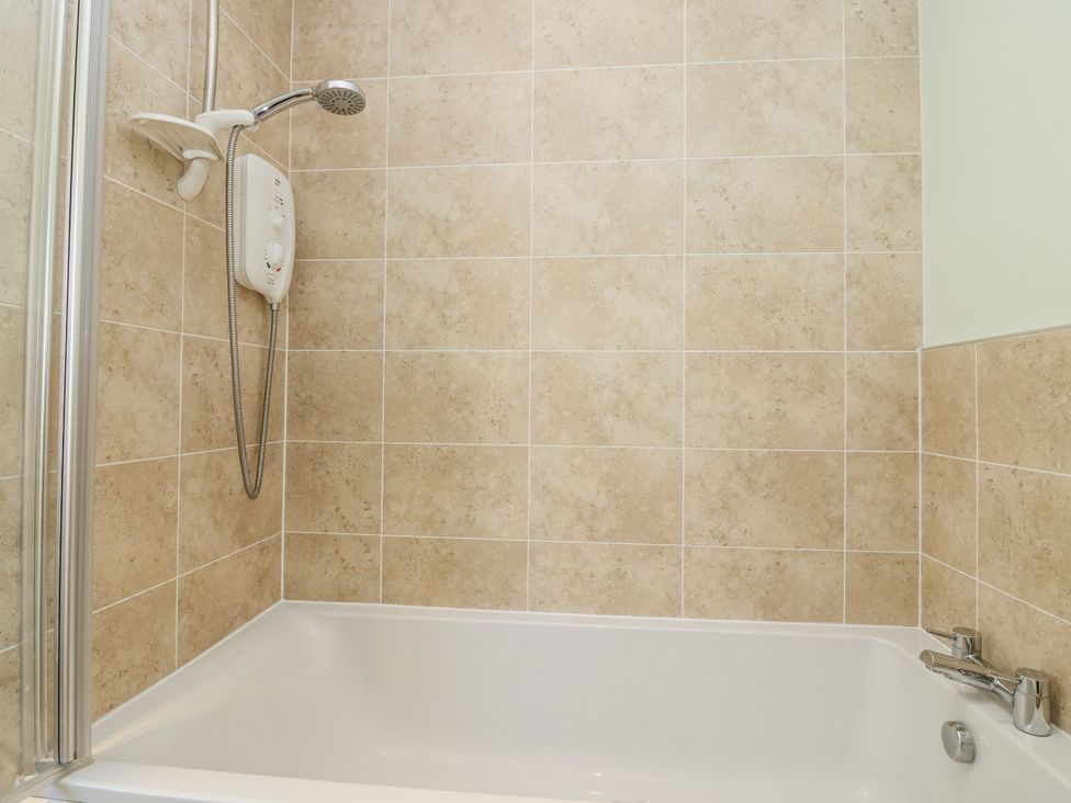 A bathroom with a bathtub and shower unit at 6A Pitlethie Steading Leuchars