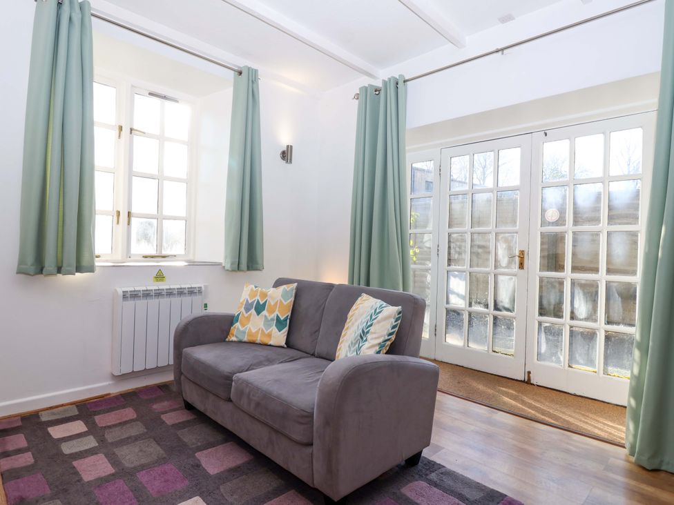 A snug with a sofa and curtains at Nest Cottage in St Tudy