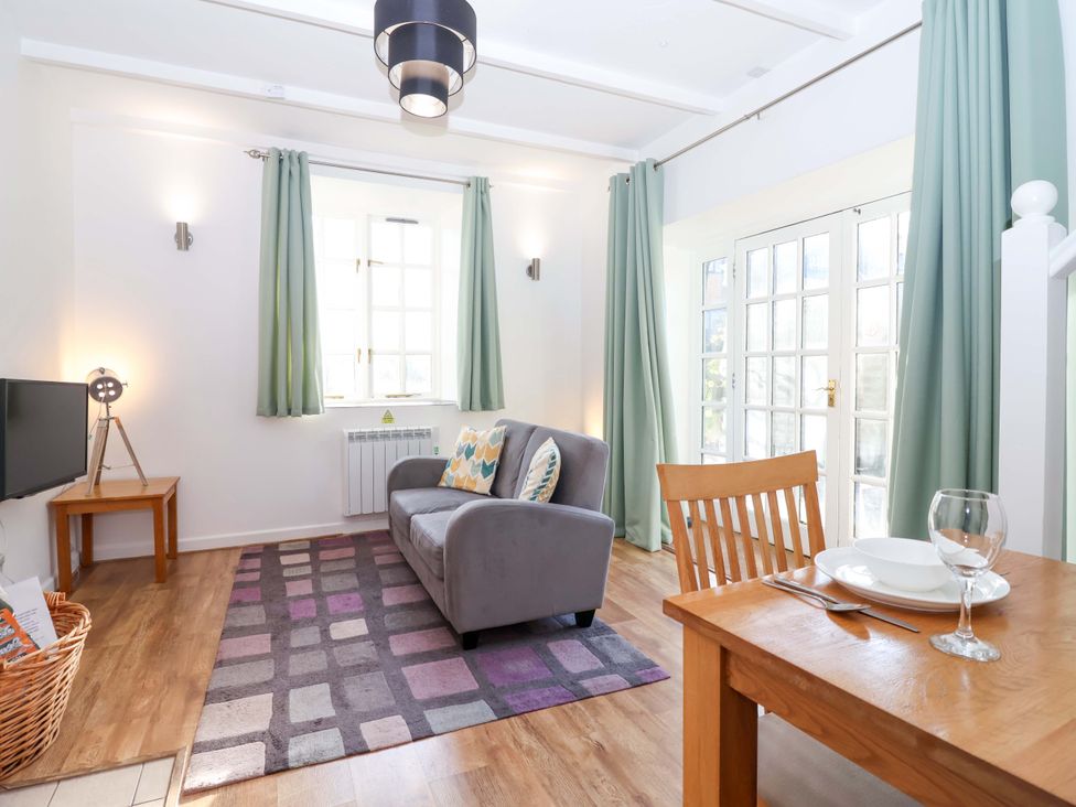 A living room with a sofa and dining table at Nest Cottage in St Tudy