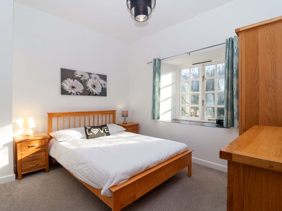 A bedroom with a bed and window at Nest Cottage in St Tudy
