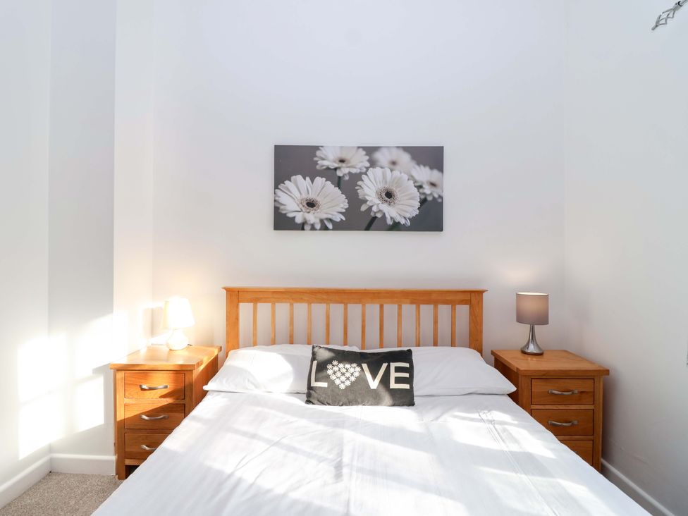 A bedroom with a bed and nightstands at Nest Cottage in St Tudy