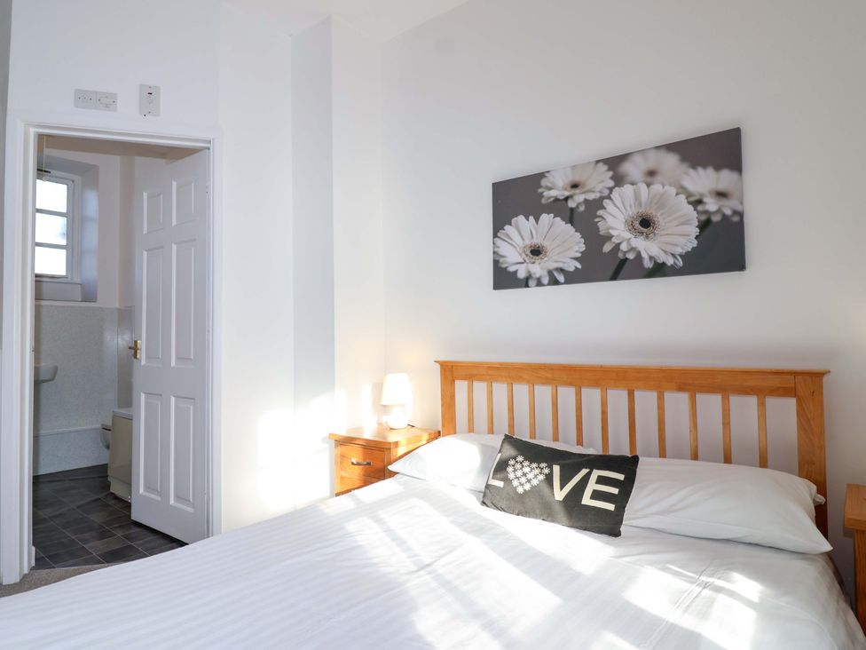 A bedroom with a bed and side table at Nest Cottage in St Tudy