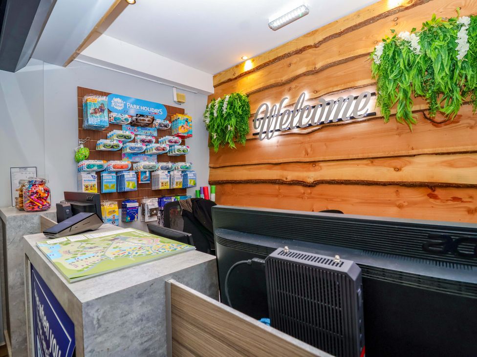 A reception desk with a brochure rack and plants at Nest Cottage in St Tudy