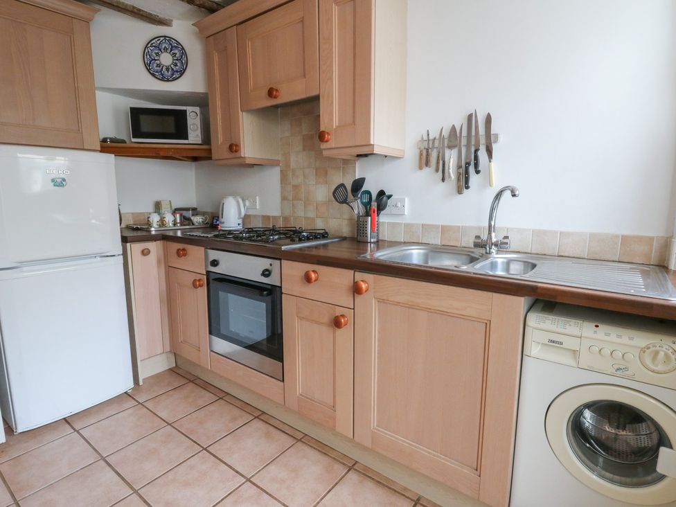 A kitchen with cabinets, a refrigerator, and a sink at 6 Church Lane Llanidloes