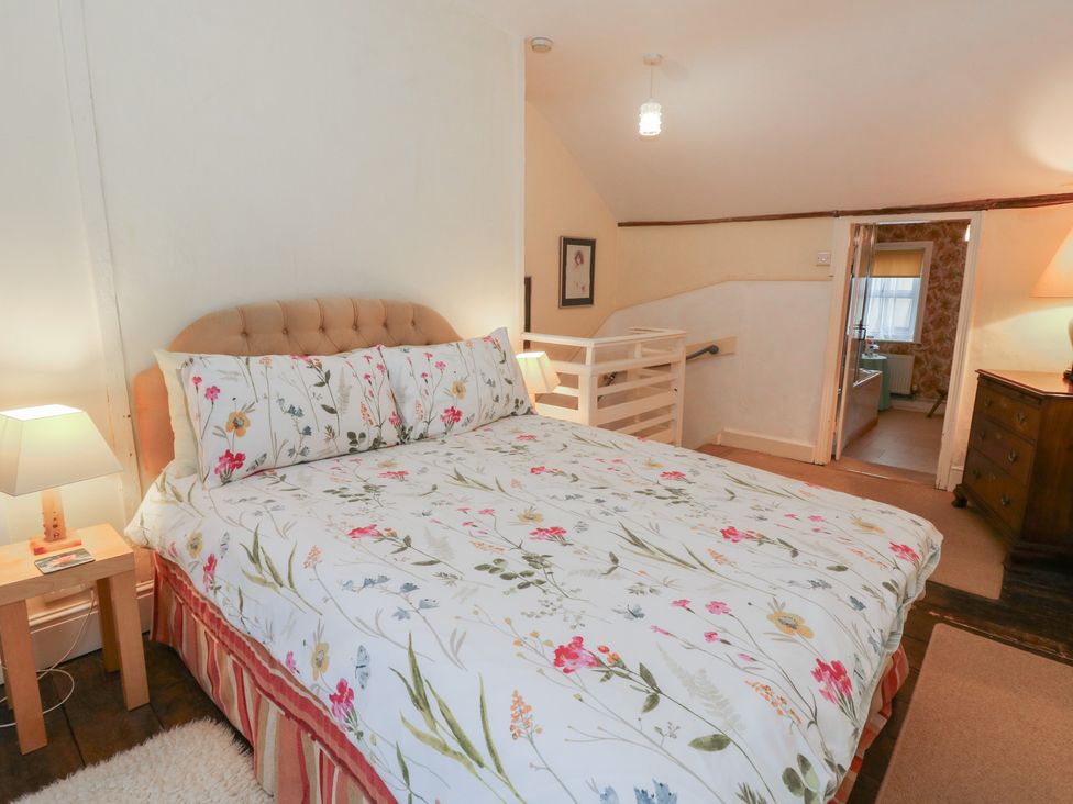 A bedroom featuring a bed with floral bedding at 6 Church Lane Llanidloes