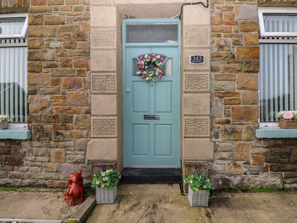 An entrance with a green door and flower baskets at Brynawel in Burry Port