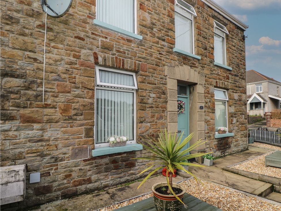 An outdoor view of a house with stone walls and a planter at Brynawel in Burry Port