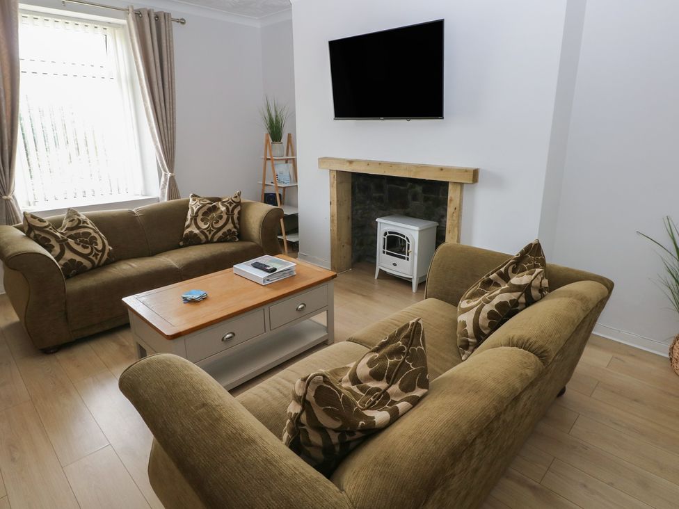 A living room with a sofa, coffee table and television at Brynawel in Burry Port