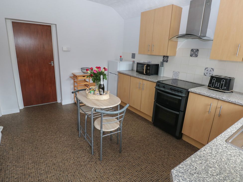 A kitchen with wooden cabinets and appliances at Brynawel in Burry Port