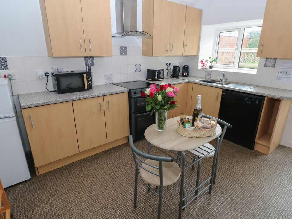 A kitchen with cabinets, appliances and a table at Brynawel in Burry Port