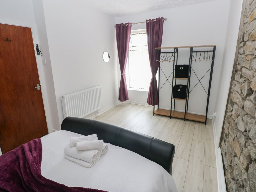 A bedroom with a bed and wardrobe at Brynawel in Burry Port
