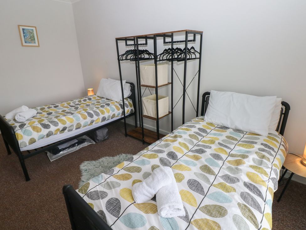 A bedroom with two beds and a clothing rack at Brynawel in Burry Port