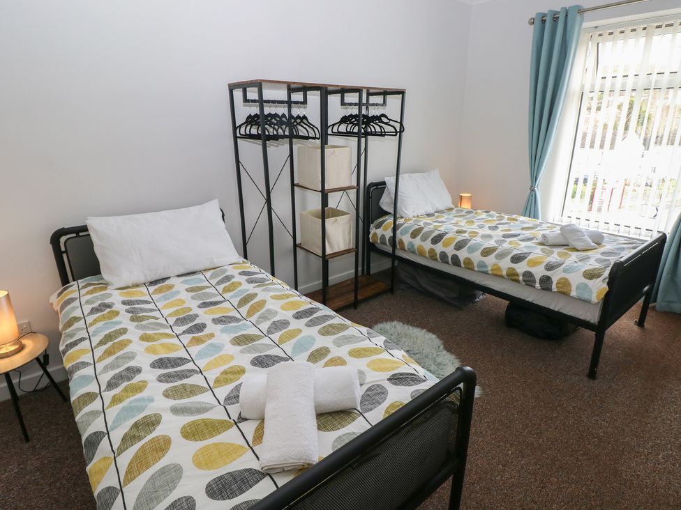 A bedroom with two beds and a clothes rack at Brynawel in Burry Port