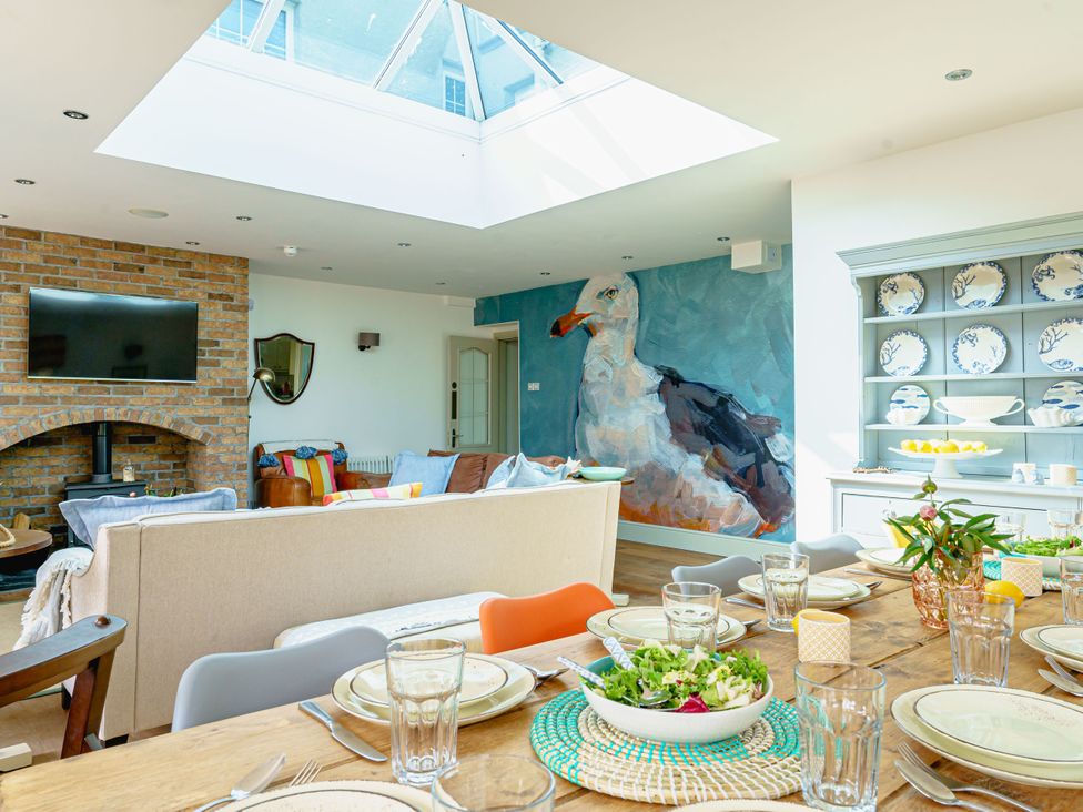 A living room with a dining area and a large bird mural at Y Graiglwyd Bull Bay near Amlwch