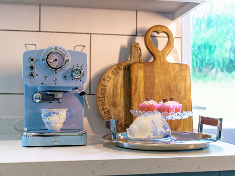 An espresso machine with a cup and cupcakes on a tray at Y Graiglwyd in Bull Bay near Amlwch