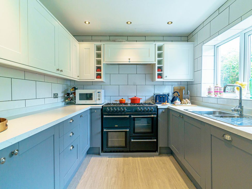 A kitchen with cabinets, oven, microwave and sink at Y Graiglwyd Bull Bay near Amlwch