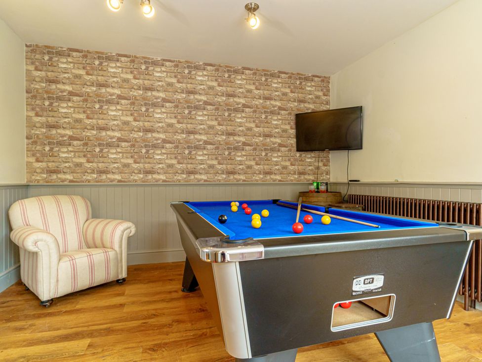 A game room with a pool table and a striped armchair at Y Graiglwyd Bull Bay near Amlwch