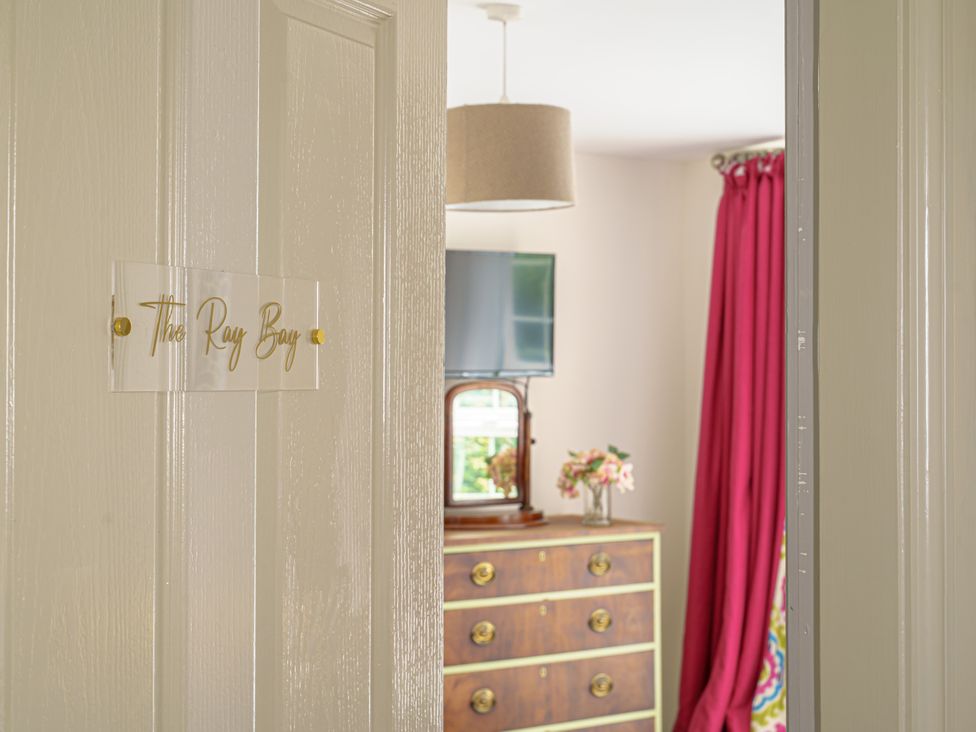 A doorway to a bedroom with a dresser and television at Y Graiglwyd Bull Bay near Amlwch