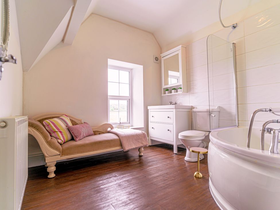 A bathroom with a bath tub and a window at Y Graiglwyd in Bull Bay near Amlwch