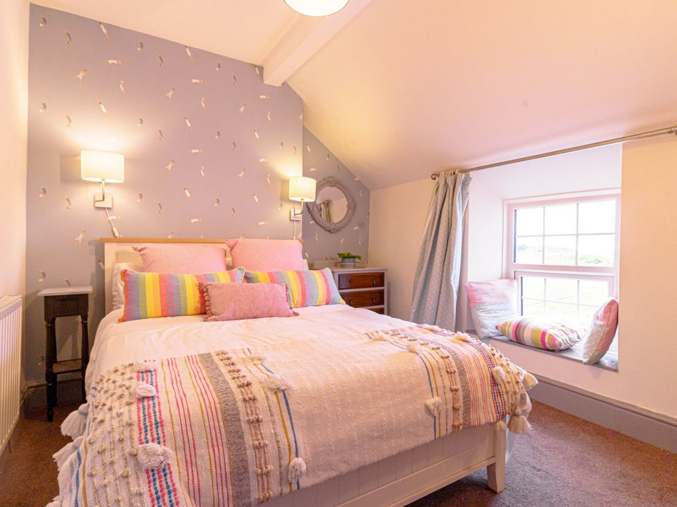 A bedroom with a bed and a window seat at Y Graiglwyd in Bull Bay near Amlwch
