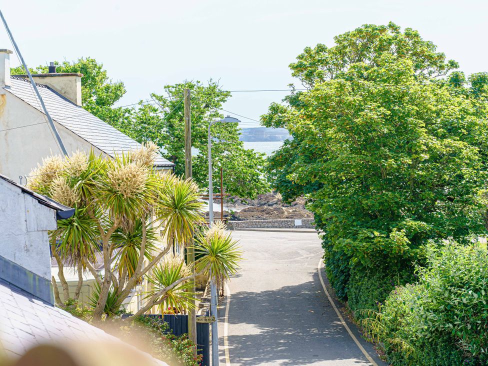 A view of a road with trees and buildings at Y Graiglwyd Bull Bay near Amlwch