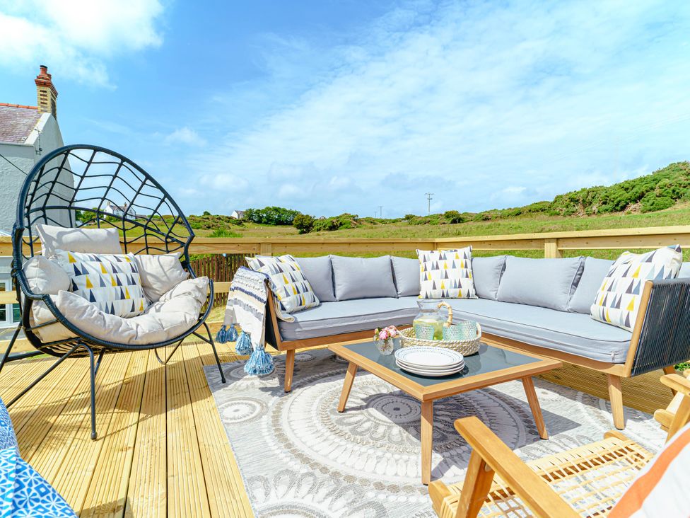 An outdoor seating area with a sectional sofa and hanging chair at Y Graiglwyd Bull Bay near Amlwch