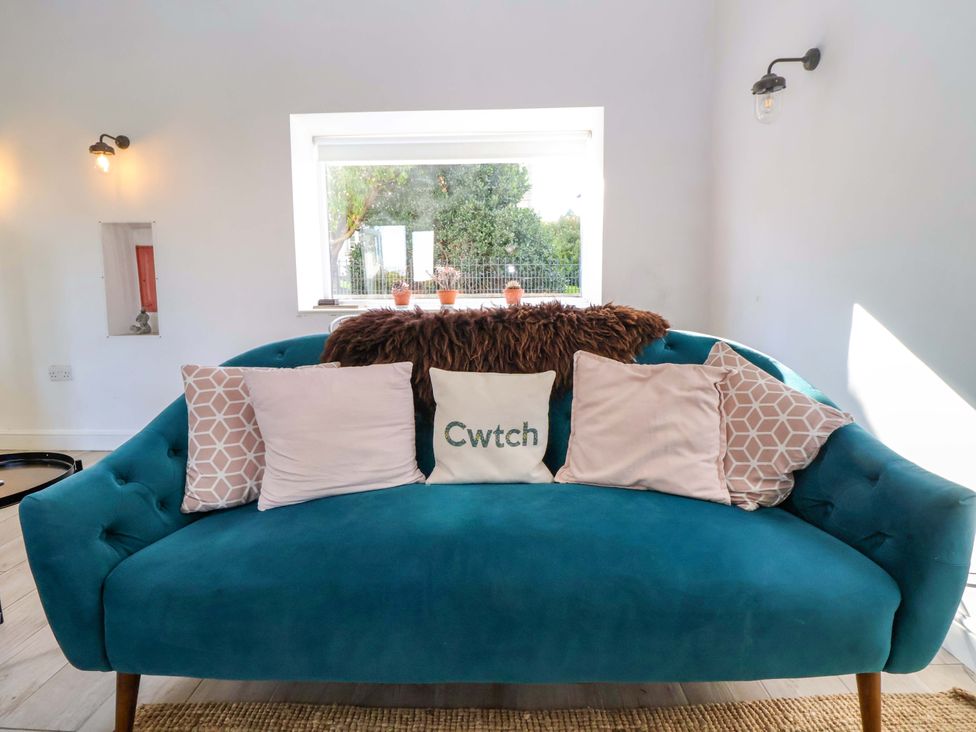 A living room with a blue sofa and cushions at Cwtch in Mold