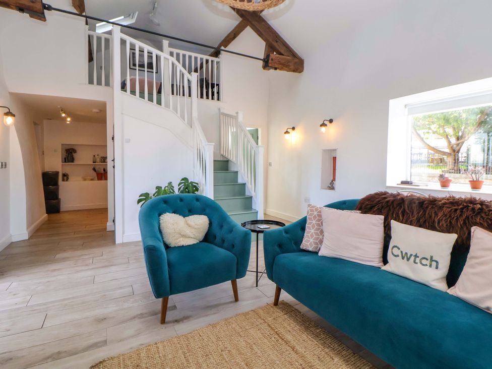 A living room with a blue sofa and staircase at Cwtch in Mold