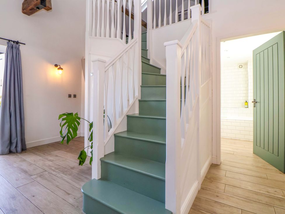 A hallway with a staircase and a door at Cwtch in Mold