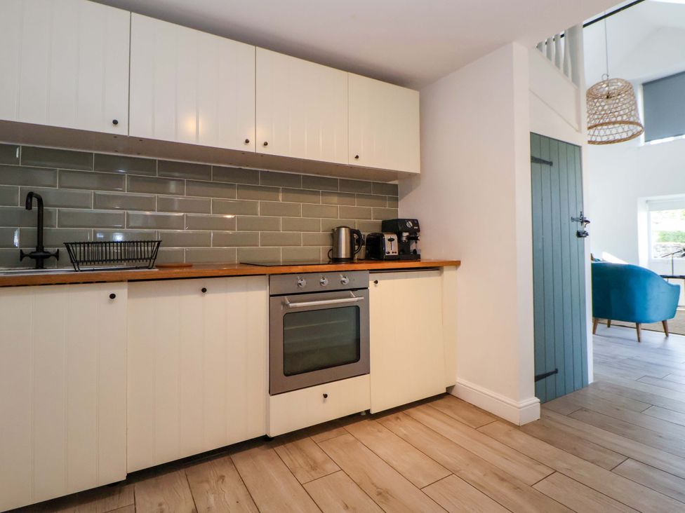 A kitchen with cabinets, stove, and coffee machine at Cwtch in Mold
