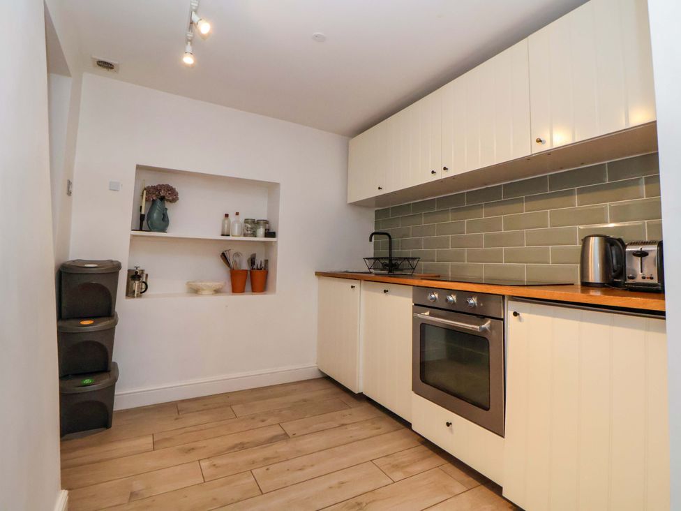 A kitchen with oven, sink, and storage at Cwtch in Mold