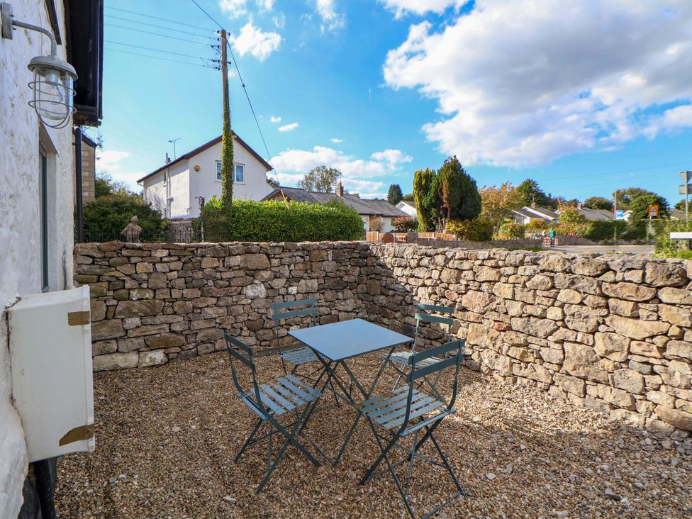 An outdoor area with a table and chairs enclosed by a stone wall at Cwtch in Mold