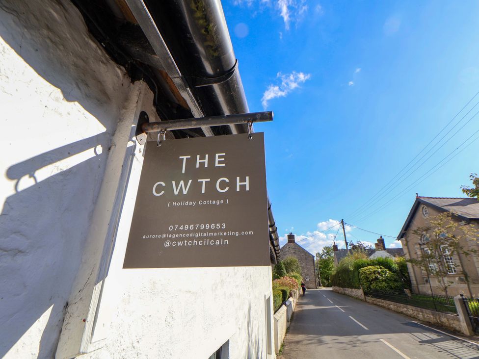 A sign for The Cwtch holiday cottage on a street in Mold