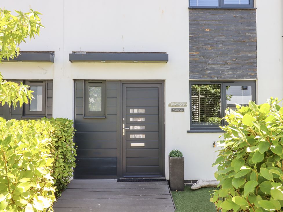 A house entrance with a door and surrounding greenery at Driftwood in Torquay