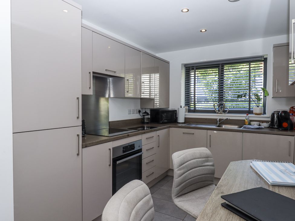 A kitchen with cabinets, stove, sink and a table at Driftwood in Torquay