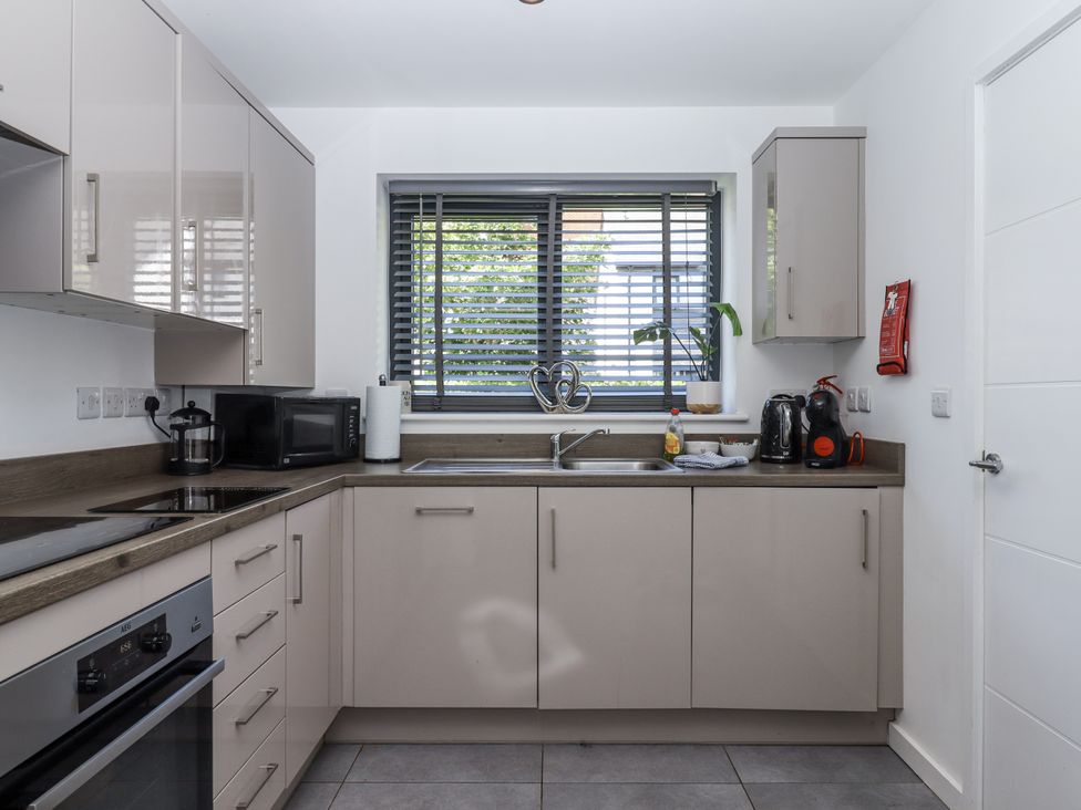 A kitchen with cabinets, sink, microwave and window at Driftwood in Torquay